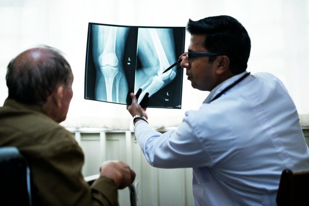 Orthopedic doctor reviewing knee X-ray for injury diagnosis at healthcare clinic.