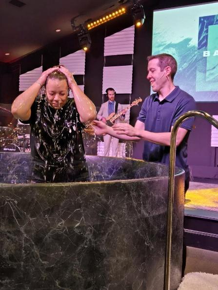 People being baptized in baptism tank at Grace Life Church with worship band in background, spiritual renewal and faith celebration.