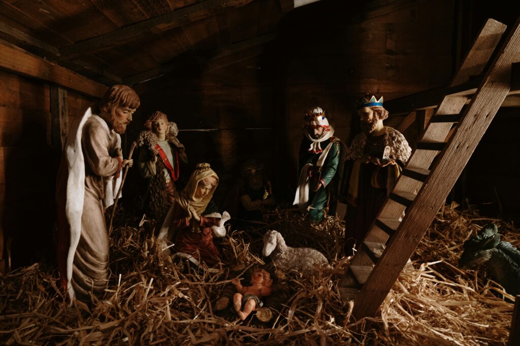 Jesus nativity scene with religious figures in a wooden stable, symbolizing Christmas celebration.